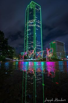 a tall building sitting next to a body of water with christmas lights on it's sides