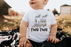 a baby sitting on top of a blanket wearing a t - shirt that says two two