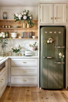 a kitchen with white cabinets and flowers on the shelves