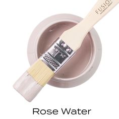 a white paint brush sitting inside of a bowl with the words rose water on it