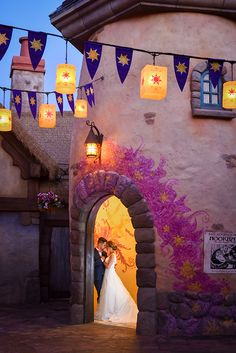 a bride and groom standing in front of a building with lanterns hanging from the roof