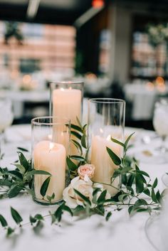 candles are sitting on a table with flowers and greenery