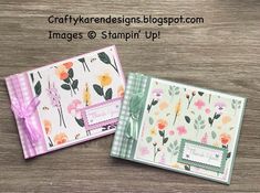 two cards with flowers on them sitting on top of a wooden table next to each other