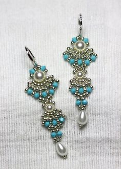 two pairs of blue and white beaded earrings with pearls on them, hanging from hooks