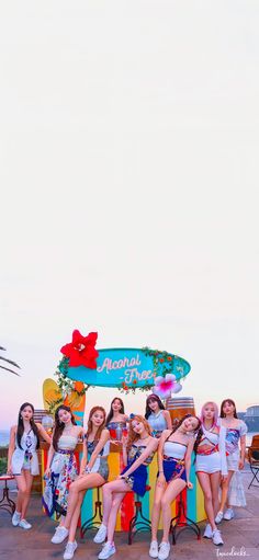 a group of young women sitting next to each other in front of a colorful sign