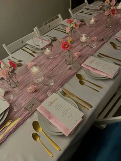 the table is set with pink and gold place settings, silverware, and napkins