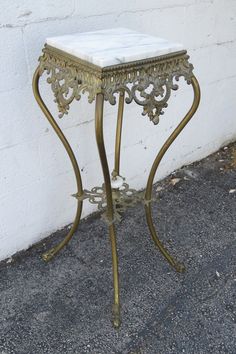 a small white table sitting on top of a cement floor next to a wall and sidewalk