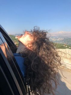 a woman with her head out the window of a car