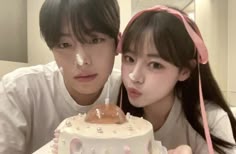 two people pose with a cake in front of them