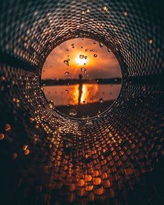 the sun is setting in front of a body of water with raindrops on it