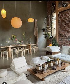 a living room filled with lots of furniture next to a table and chairs in front of a brick wall