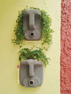 two cement planters with plants growing in them on the side of a yellow wall