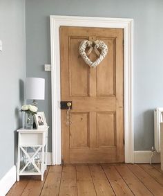 a heart shaped wreath hangs on the front door of a room with blue walls and wooden floors