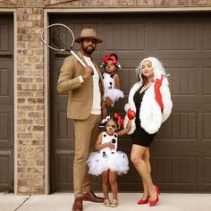 a man and two girls dressed up in costumes standing next to a garage door holding tennis rackets