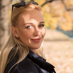 a woman with long blonde hair and sunglasses on her head, smiling at the camera