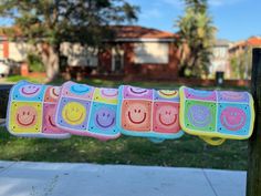 colorful crocheted potholders hanging from a wooden pole in front of a house