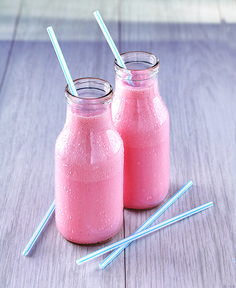 two jars with straws are sitting on a table next to each other, one has pink liquid and the other is blue