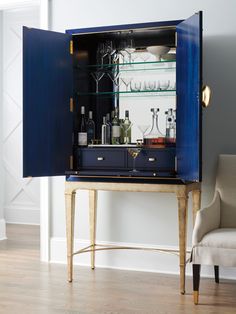 a blue cabinet with wine glasses and bottles in it is open to reveal a bar