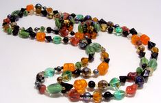 "Long Strand Necklace of Multi Color Glass Beads and Matching Clip Earrings. Glass Bead Colors Are: Orange, Green, Black, White, Gold and Blue Iridescent. Each Color Bead is a Different Shape and Type Such as : Orange-Barrel-Crackel, Green-Oval- Molded Cats Eye, White-Round-Clear, Blue Iridescent Carnival-Round, Gold-Faceted-Round, Etc. Necklace is 50\" Long and Can be Worn Long or Doubled or Tripled. Earrings Are 1\" in diameter and Stamped Made in West Germany. Colorful and Unusual! Necklace a Unique Czech Glass Jewelry For Party, Vintage Czech Glass Jewelry For Party, Costume Jewelry With Czech Glass For Party, Party Costume Jewelry With Czech Glass, Czech Glass Costume Jewelry For Parties, Vintage Multicolor Jewelry With Faceted Beads, Multicolor Czech Glass Jewelry For Party, Party Jewelry With Faceted Glass Beads, Multicolor Czech Glass Party Jewelry