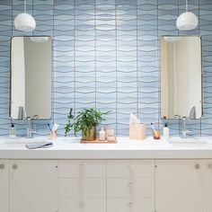 a bathroom with two sinks and mirrors on the wall next to each other in front of a blue tile backsplash