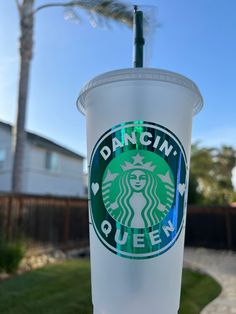 a plastic cup with the word dancin's queen on it sitting in front of a palm tree