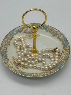 a plate with pearls on it and a keychain hanging from the handle that says love