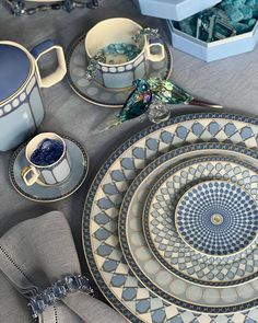 a table topped with plates and cups filled with blue liquid next to silverware on top of a cloth covered table