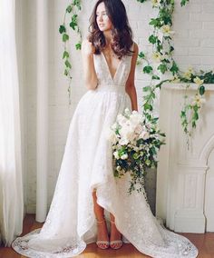 a woman standing in front of a fireplace wearing a white dress and holding a bouquet