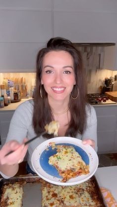 a woman holding a plate of food in her hands and eating it with a fork