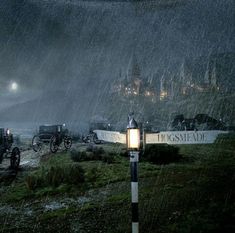 a group of horses pulling carriages down a road in the rain at night with lights on