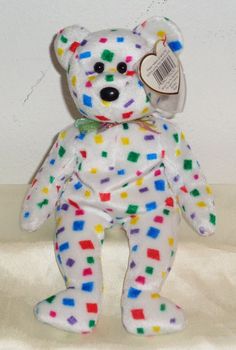 a white teddy bear with multicolored spots on it's body