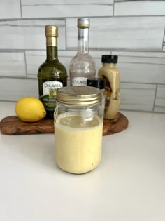 a jar filled with liquid sitting on top of a counter next to bottles and lemons