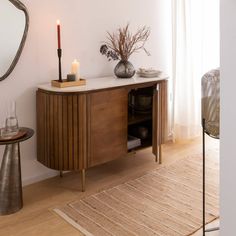 a room with a table, mirror and vases on the sideboard in it