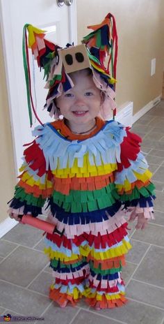 a young child wearing a costume made out of strips of colored paper with a cat mask on it's head