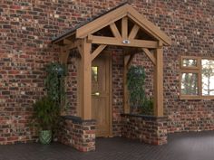 a brick building with a wooden door and window on the side walk next to potted plants