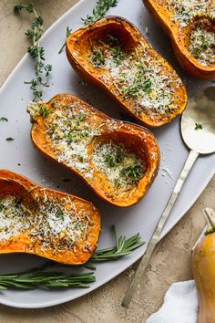 four stuffed butternut squash on a white plate with herbs and parmesan sprinkles