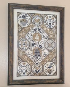 a framed cross stitch pattern hanging on the wall