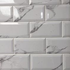 a white tile backsplash with grey veining