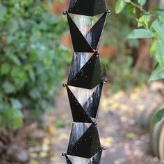 a black and white wind chime hanging from a tree in front of some trees