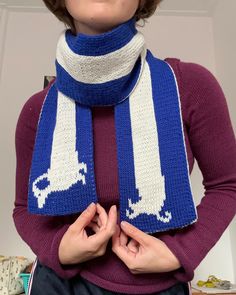 a woman wearing a blue and white knitted scarf with the letter l on it