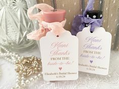 two small tags are sitting next to each other on a lace tablecloth with pearls