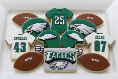 decorated cookies in the shape of footballs and jerseys are arranged on a white platter