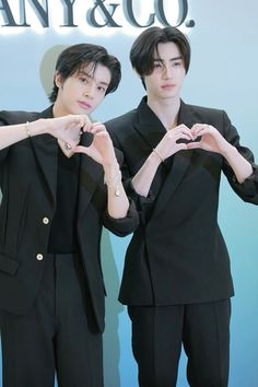 two young men standing next to each other with their hands in the shape of a heart