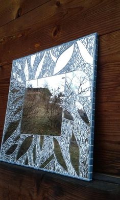 a mirror that is on the side of a wooden wall next to a tree and grass