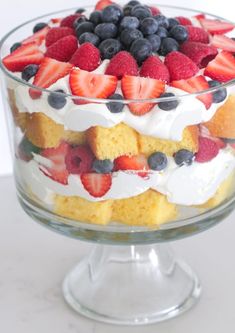 a layered cake with strawberries and blueberries on top