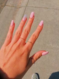 a woman's hand with pink and white manicures on it, holding her ring