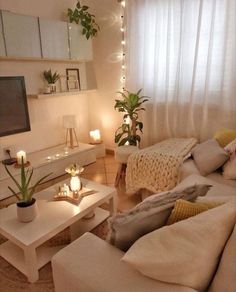 a living room filled with white furniture and lots of lights on the windows sill