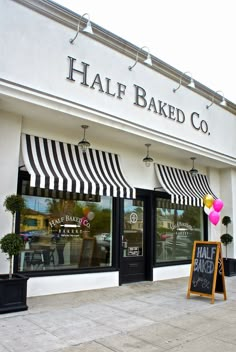 the front of a bakery with black and white awnings on it's windows