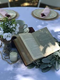 an open book sitting on top of a table next to a vase filled with flowers