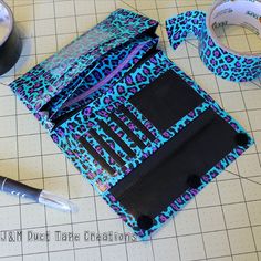 a blue and black leopard print bag next to a roll of tape with scissors on it